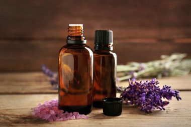 Aroma yağı, deniz tuzu ve lavanta çiçekleri ahşap arka plan üzerinde şişesiyle