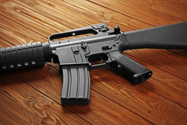 Close up view of assault rifle on wooden background clipart