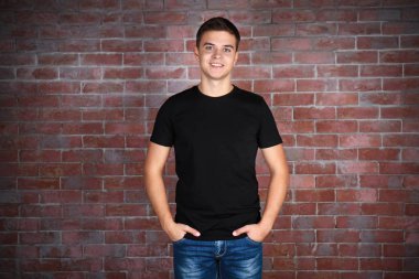 Yakışıklı delikanlı boş siyah t-shirt ayakta duvara karşı