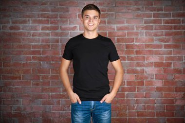 Yakışıklı delikanlı boş siyah t-shirt ayakta duvara karşı