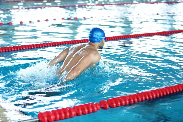 Молодой человек плавает в бассейне — стоковое фото