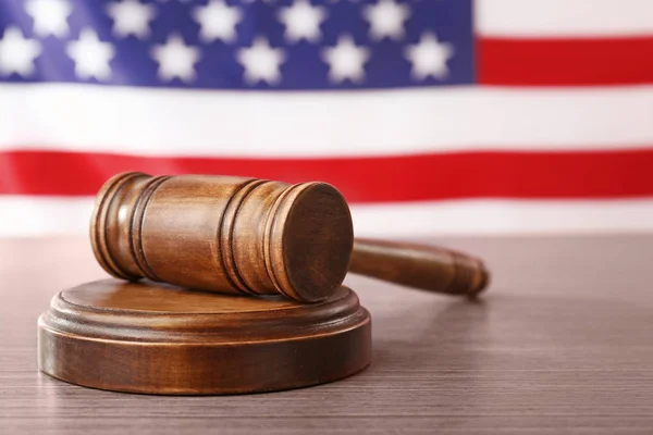 Wooden gavel on table against blurred USA flag — Stock Photo, Image