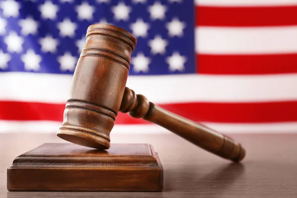 Wooden gavel on table against blurred USA flag — Stok Foto