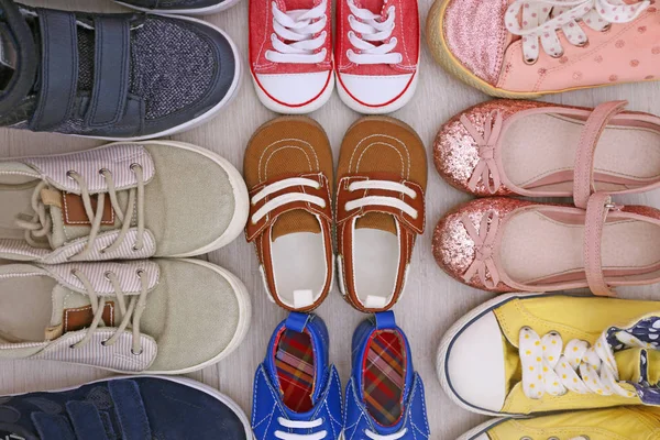 Buty dziecięce różnych na drewnianej podłodze, widok z góry — Zdjęcie stockowe