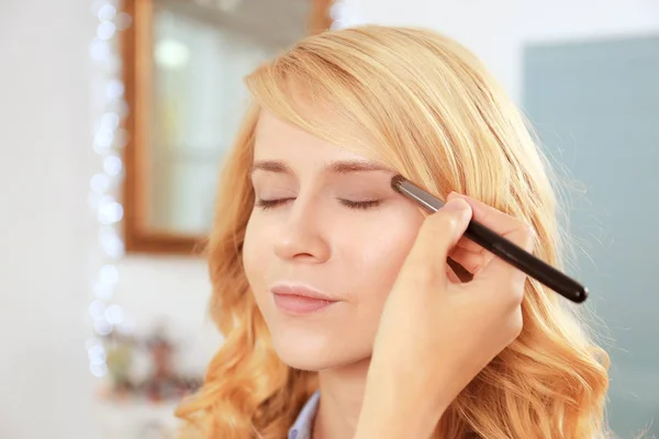 Artista aplicando sombra de ojos en hermosos ojos de mujer —  Fotos de Stock