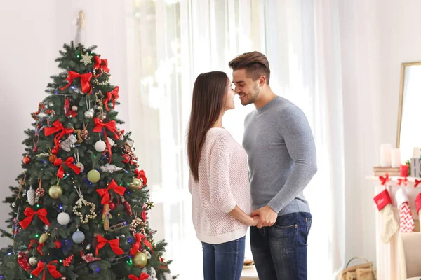 Pareja joven cerca del árbol de Navidad en la habitación — Foto de Stock