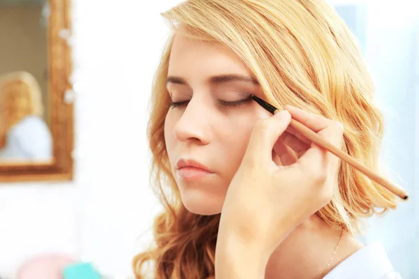 Artista aplicando sombra de ojos en hermosos ojos de mujer — Foto de Stock