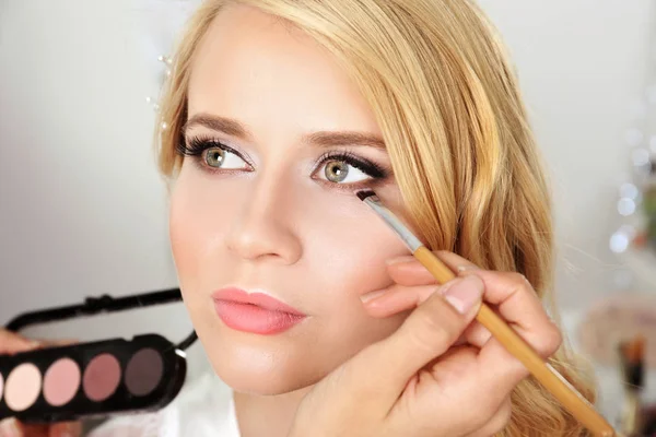 Kunstenaar toepassing van oogschaduw op mooie vrouw ogen — Stockfoto