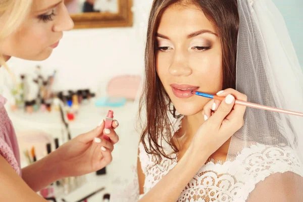 Préparation du mariage. Maquilleuse professionnelle appliquant du brillant à lèvres sur les lèvres de la mariée — Photo