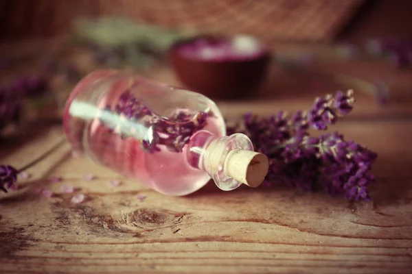 Garrafa com óleo de aroma e flores de lavanda em fundo de madeira — Fotografia de Stock