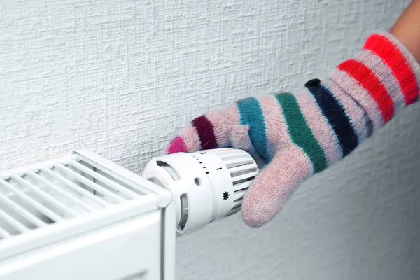 Mujer sosteniendo la perilla de temperatura del radiador de calefacción —  Fotos de Stock