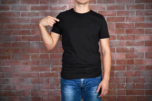 Ember üres fekete póló állandó ellen téglafal, közelről — Stock Fotó