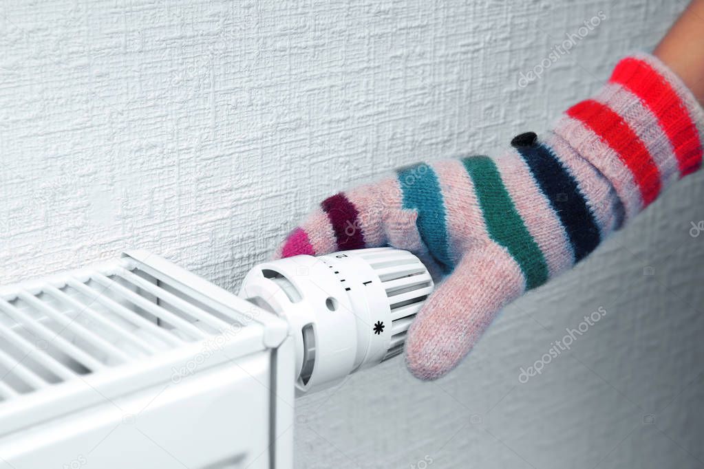 Woman holding temperature knob of heating radiator