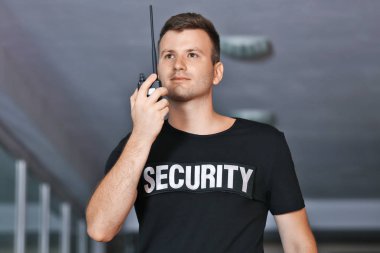 Güvenlik adam koridorda taşınabilir radyo kullanarak