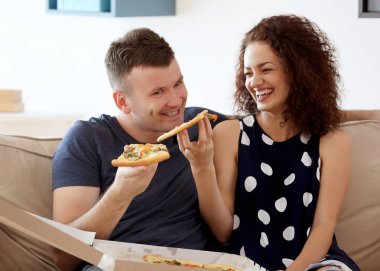 Evde pizza yiyen genç bir çift.