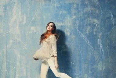 Gri arka planda poz veren güzel bir kadın.