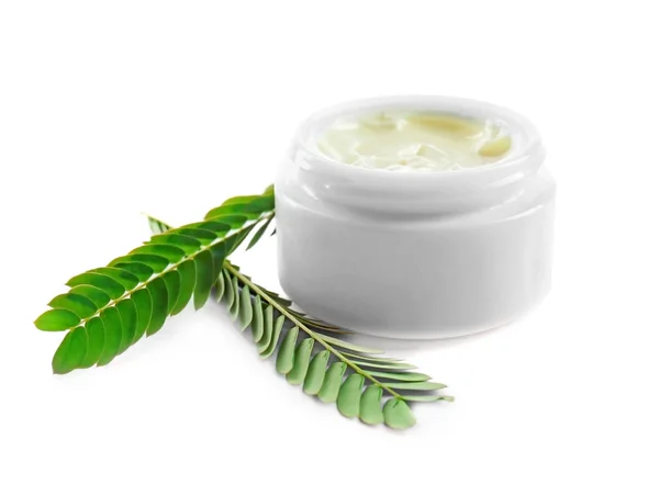 Gesichtscreme und grüne Blätter auf weißem Hintergrund — Stockfoto