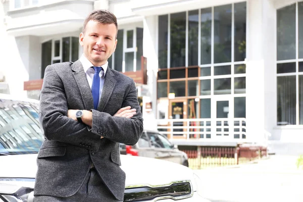 Businessman standing near a car on a street — Stock Photo, Image