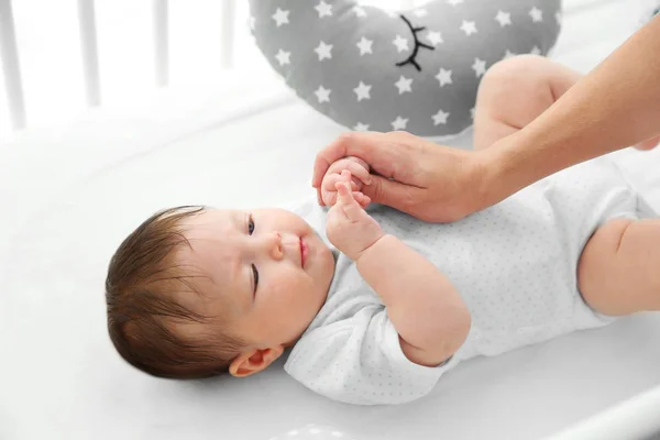 Söt baby i sängen med mamma hand — Stockfoto