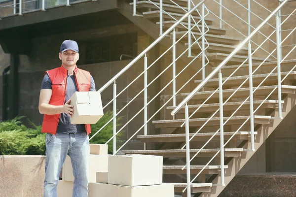 Jovem entregador masculino com caixas ao ar livre — Fotografia de Stock
