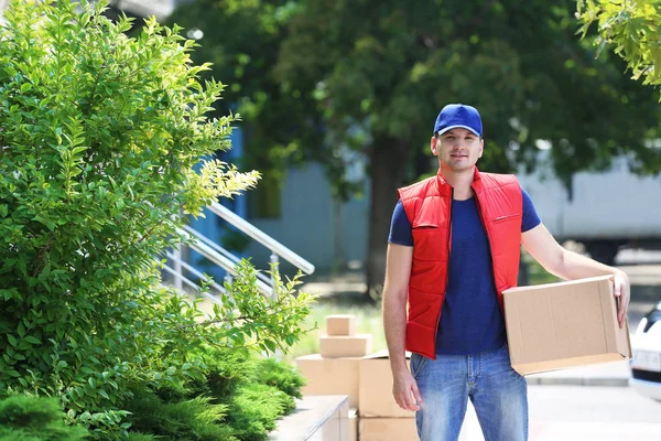 Repartidor masculino joven con caja al aire libre —  Fotos de Stock