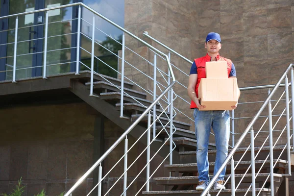 Jovem entregador masculino com caixas ao ar livre — Fotografia de Stock