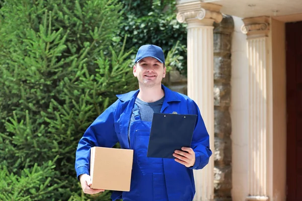 Young male deliverer with box in yard — Stock Photo, Image