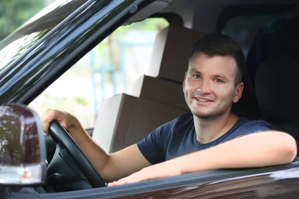 Repartidor masculino joven con cajas sentadas en coche —  Fotos de Stock