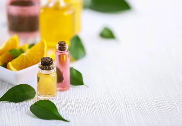 Botellas con aceite esencial y hojas sobre mesa de madera — Foto de Stock