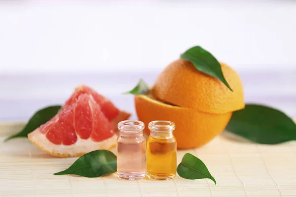 Flaschen mit ätherischem Öl, Grapefruit und Blättern auf Bambusserviette — Stockfoto