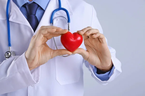 Manos de médico masculino sosteniendo el corazón rojo sobre fondo claro —  Fotos de Stock