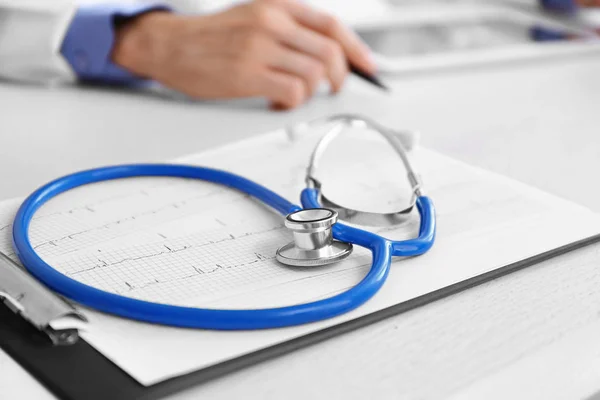 Кліпборд, стетоскоп і кардіограма на столі лікаря — стокове фото