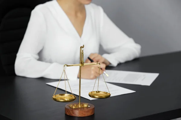 Весы правосудия и деловая женщина, сидящая за столом — стоковое фото
