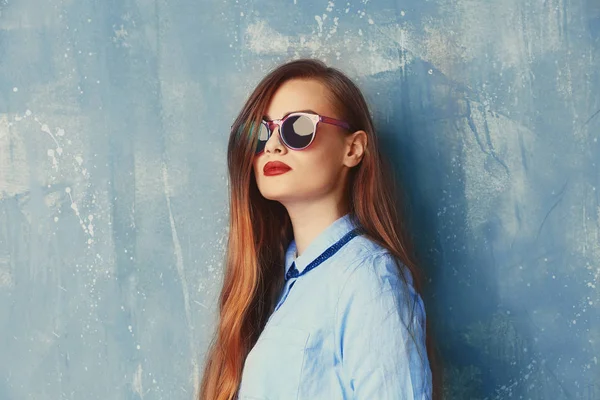 Şık kadın mavi tişört ve gri arka plan üzerinde güneş gözlüğü — Stok fotoğraf