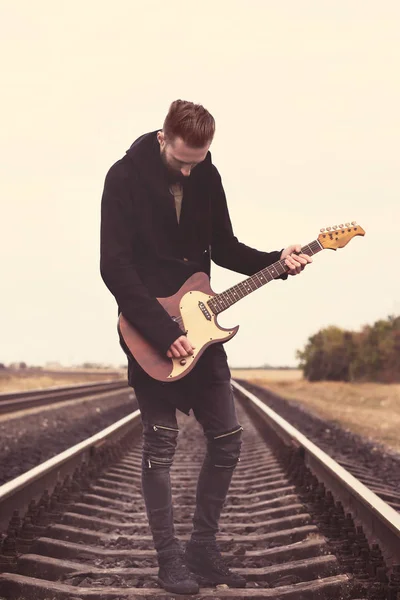 Bello uomo con chitarra su ferrovia — Foto Stock