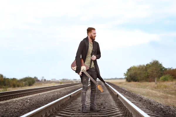 Schöner Mann mit Gitarre auf der Eisenbahn — Stockfoto