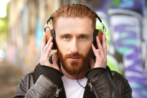 Hombre guapo en auriculares escuchando música al aire libre — Foto de Stock