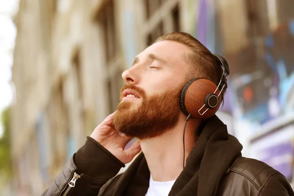 Hombre guapo en auriculares escuchando música al aire libre —  Fotos de Stock