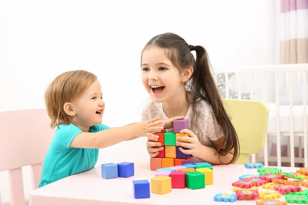 Милая девочка играет с младшей сестрой дома — стоковое фото
