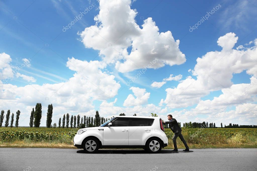 Man pushing damaged car