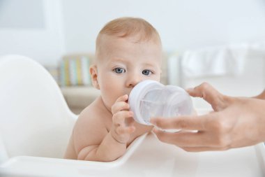Su bebek şişe, closeup içmek için veren anne