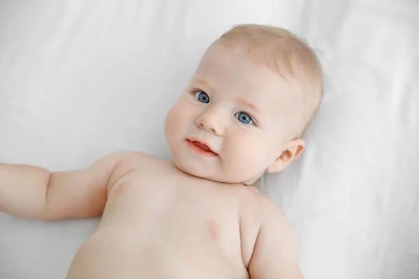 Kis baba, fehér ágy portréja — Stock Fotó
