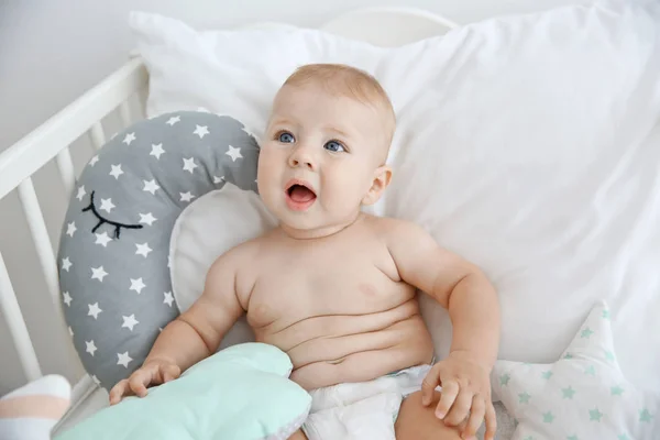 Niedliches kleines Baby mit Kissen im Kinderbett — Stockfoto