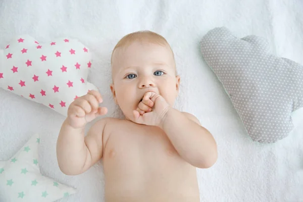 Cute little baby with pillows on white bed, closeup — Stock Photo, Image