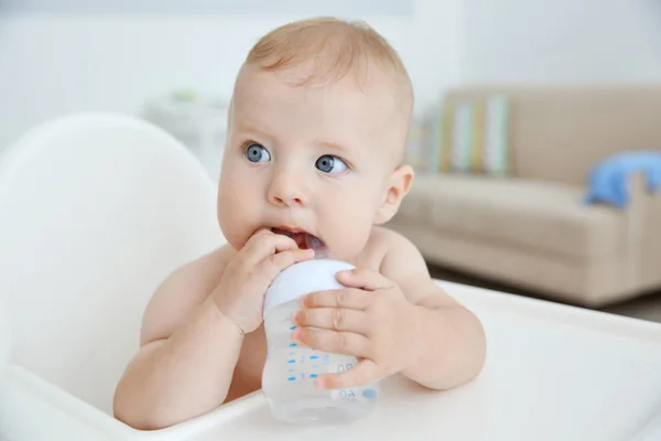 Little baby drinking water from bottle indoors — Stock Photo, Image