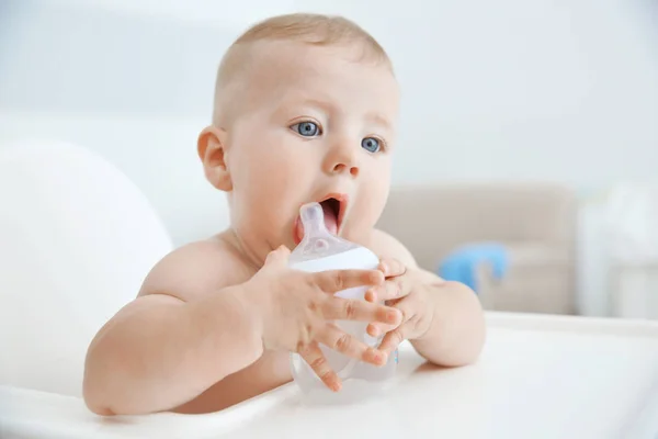 Малыш пьет воду из бутылочки в помещении — стоковое фото