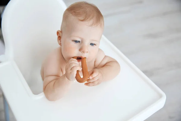 Pequeno bebê comendo bagel dentro de casa — Fotografia de Stock