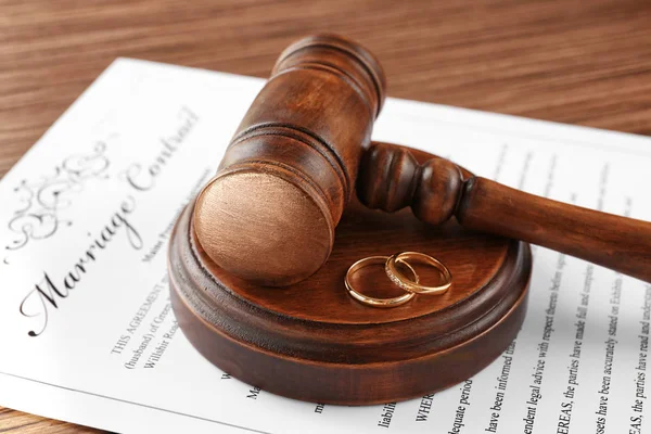 Golden wedding rings with judge gavel on marriage contract, closeup — Stock Photo, Image