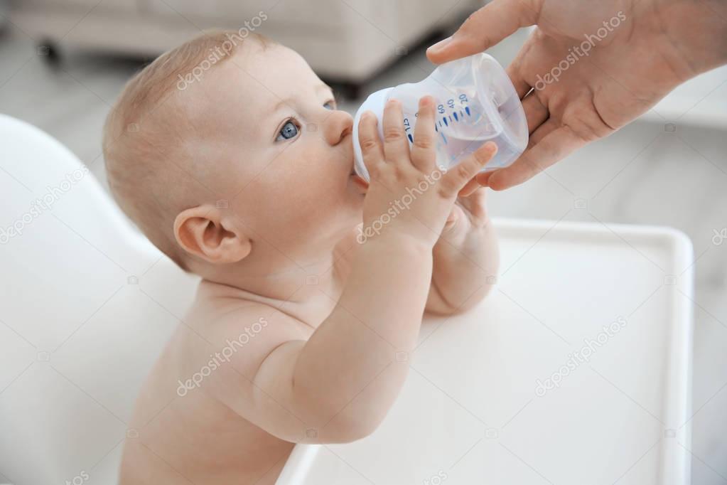 Mother giving to drink water baby from bottle, closeup