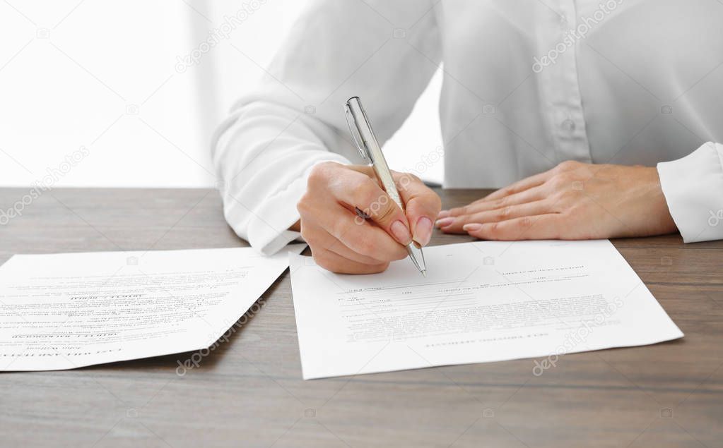 Successful businesswoman signing documents in office, close up view